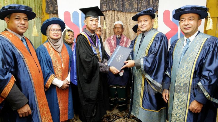 Abdul Halim menerima ijazah sarjana muda daripada Noor Azizi (dua kanan) di rumahnya di Kampung Kok Kiak Baka. FOTO Fathil Asri