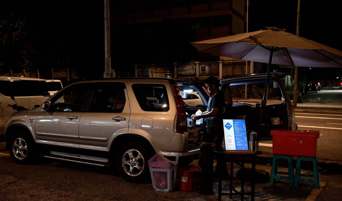 MOHAMAD Hazreel yang mengusahakan ‘kedai kopi’ meskipun ruang terhad di bahagian but kereta jenis Honda CRV milik keluarganya. FOTO BERNAMA