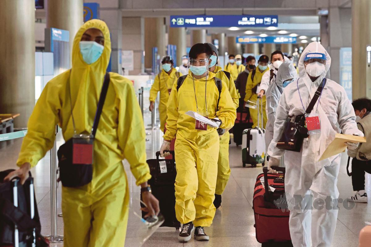 PENUMPANG memakai pakaian perlindungan diri ketika tiba di Lapangan Terbang Incheon, Korea Selatan. Negara itu sudah menyekat kemasukan pengembara asing dari lapan negara Afrika susulan varian Omicron. FOTO EPA 