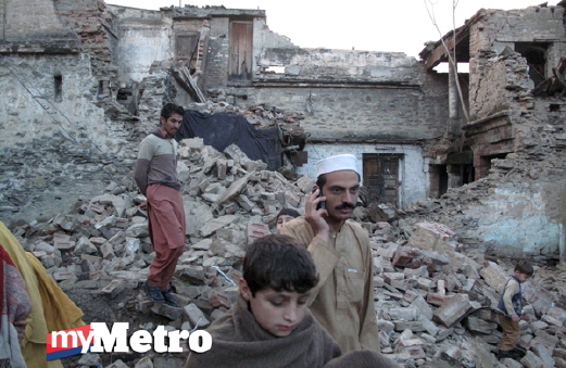 Penduduk berjalan di atas runtuhan rumah di Mingora, Swat, Pakistan, dekat sempadan Afghanistan, yang musnah akibat gempa bumi melanda Jurm, Afghanistan, berdekatan sempandan Pakistan, petang semalam. - Foto REUTERS