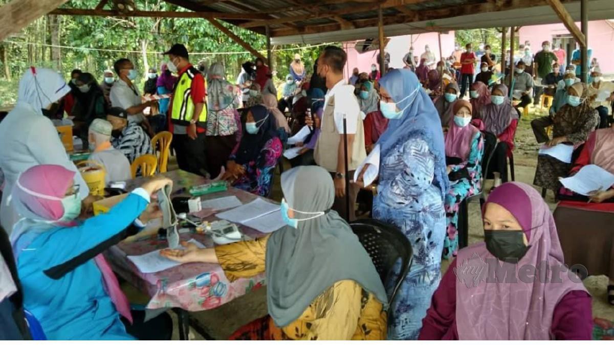 SEBAHAGIAN penduduk kampung mendaftar untuk mendapatkan suntikan vaksin di pekarangan Masjid Kampung Bahagia, Kuala Krai, hari ini. FOTO HAZIRA AHMAD ZAIDI