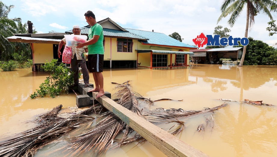 Mangsa banjir di di Kampung Tubuh Panchor Bagan Serai, Perak, Musa Nusi (kiri) memindahkan barang keluar dari rumahnya. - Foto L  MANIMARAN