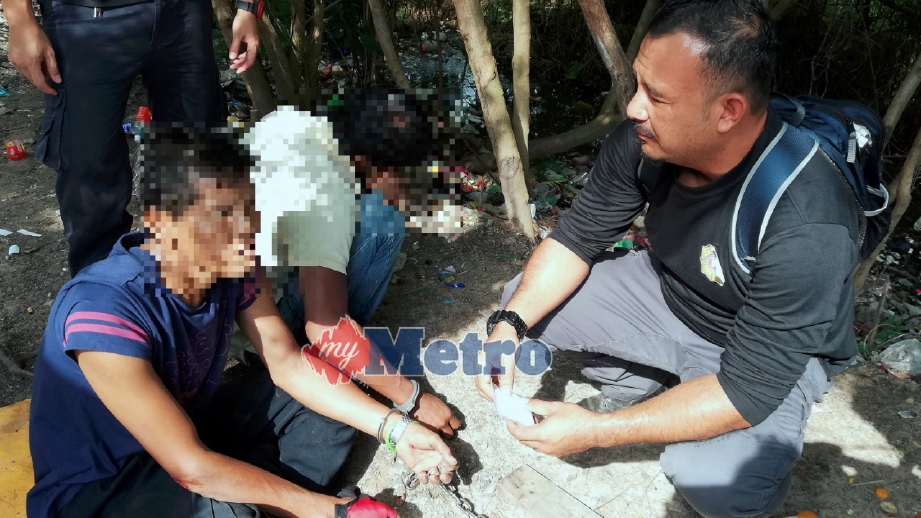  PEGAWAI AADK memeriksa penagih yang ditahan di bekas tapak pelupusan sampah Krubong. FOTO Zairee Mohd Yasak