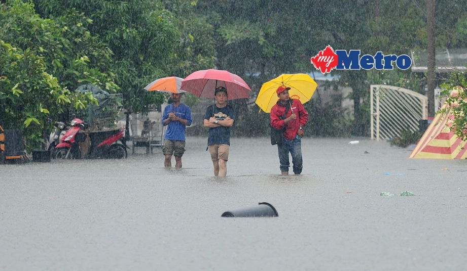 Penduduk mengharungi banjir berikutan hujan lebat sejak malam tadi di Taman Sri Intan 2, Jalan Sultan Omar. - Foto MOHD SYAFIQ RIDZUAN AMBAK