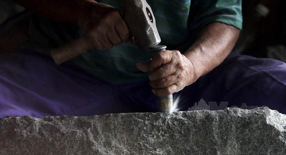 KUAH mengukir batu granit untuk dijadikan batu nisan. FOTO Saddam Yusoff