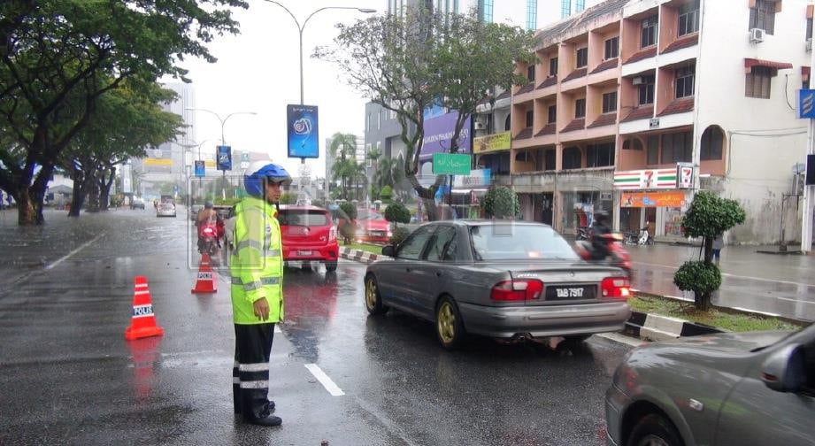 Anggota polis trafik menjaga lalu lintas yang sesak berikutan berlaku banjir kilat akibat hujan lebat sejak awal pagi tadi di jalan Sultan Omar menghala ke Wisma Darul Iman, Kuala Terengganu. FOTO Imran Makhzan