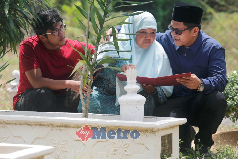 MUHAMMAD Syauqellah (kanan) bersama Zainab dan abangnya, Muhammad Shahrul Aiman, 20, menziarahi pusara bapanya di Tanah Perkuburan Islam Kampung Gong Tok Nasek, Kuala Terengganu selepas mendapat keputusan 11A dalam SPM. FOTO Rozainah Zakaria
