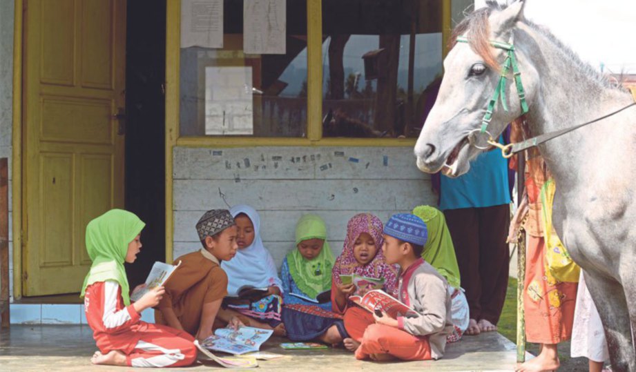 KANAK-KANAK desa membaca buku yang dibawa Ridwan.