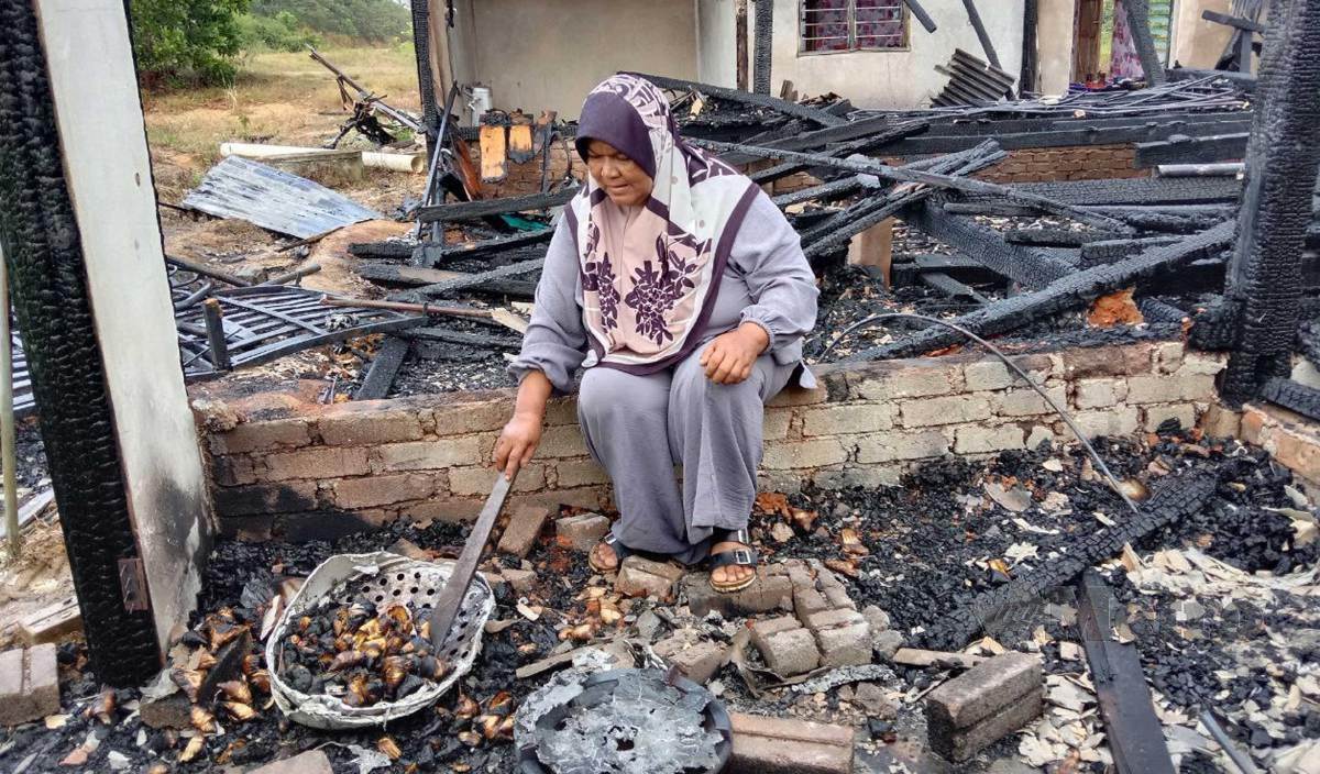 ROSLINA melihat keadaan rumahnya yang hangus dalam kebakaran di Kampung Bukit Ara. FOTO Nazdy Harun
