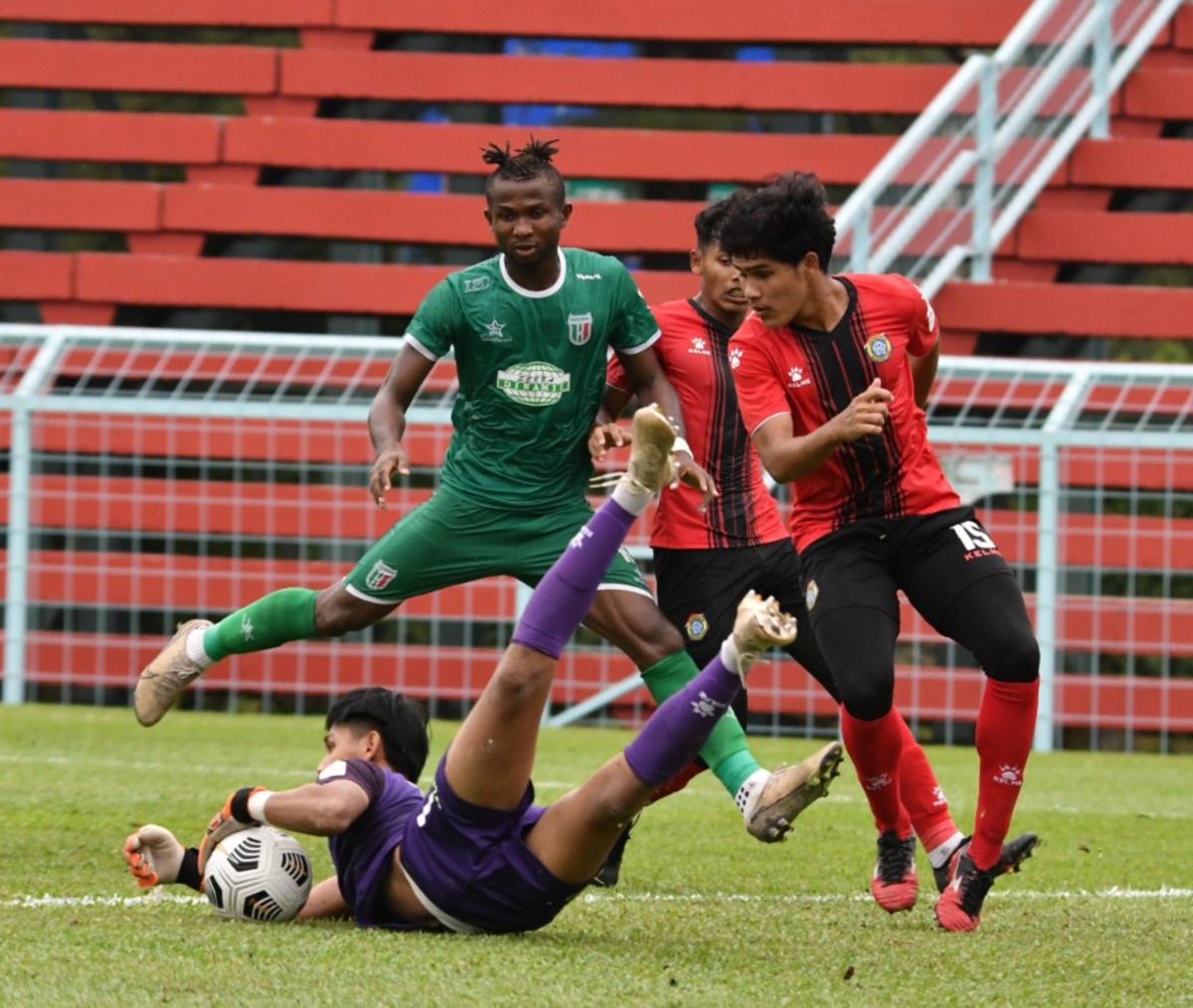 Penjaga gol skuad Projek FAM-MSN, Al-Iman Wahiey Muhammad Amir (kiri) berjaya menangkap bola ketika diasak pemain Kuching City FC pada aksi Liga Perdana di Stadium MBPG. FOTO Ihsan Kuching City FC.