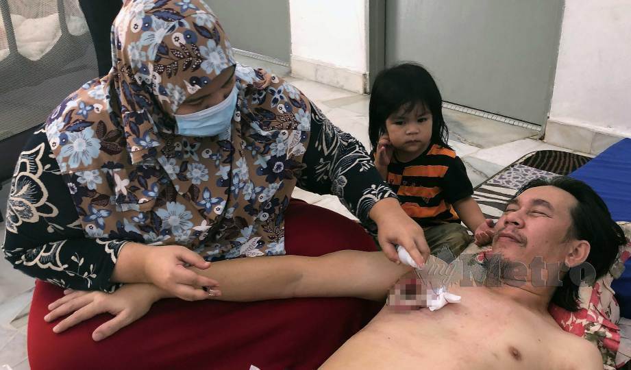 SITI Sapiah (kiri) membersihkan luka suaminya, Md Fairul yang menghidap barah payudara di Pangsapuri Lagoon Perdana, Bandar Sunway. FOTO Amirudin Sahib