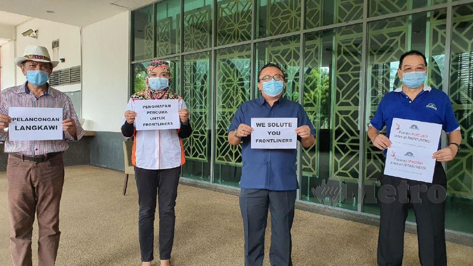  RAZMI (kanan) bersama rakannya menunjukkan kertas bertulis tawaran percuma kepada petugas barisan hadapan bercuti di Langkawi. FOTO Hamzah Osman