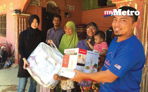 CHAZALI (kanan) menyerahkan barangan keperluan rumah kepada penduduk kampung di Kuala Sungai, Gua Musang.