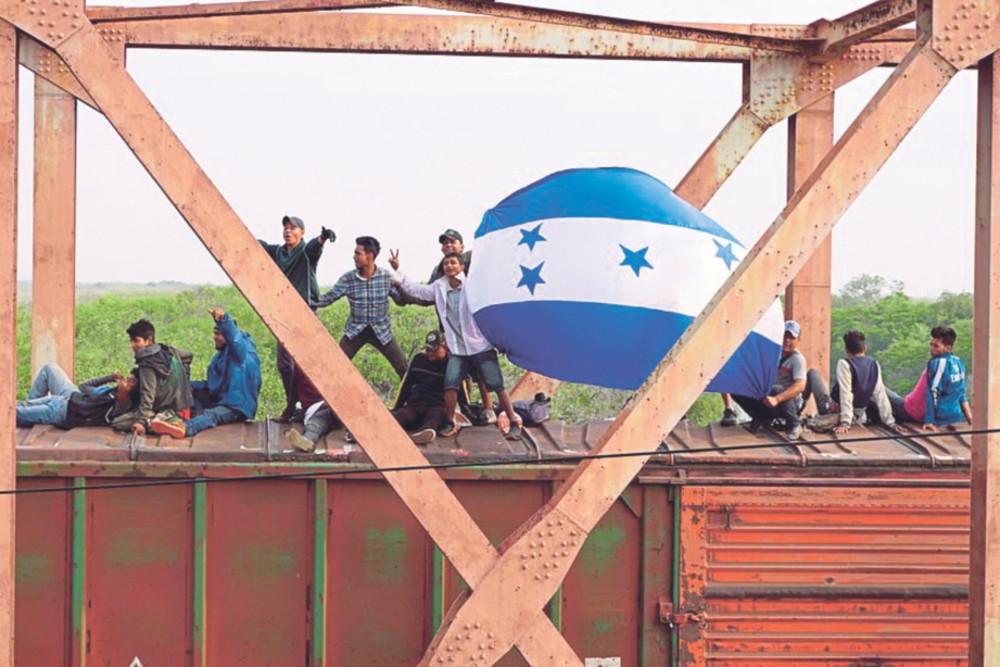 PELARIAN dari Honduras mengibarkan bendera negara mereka.