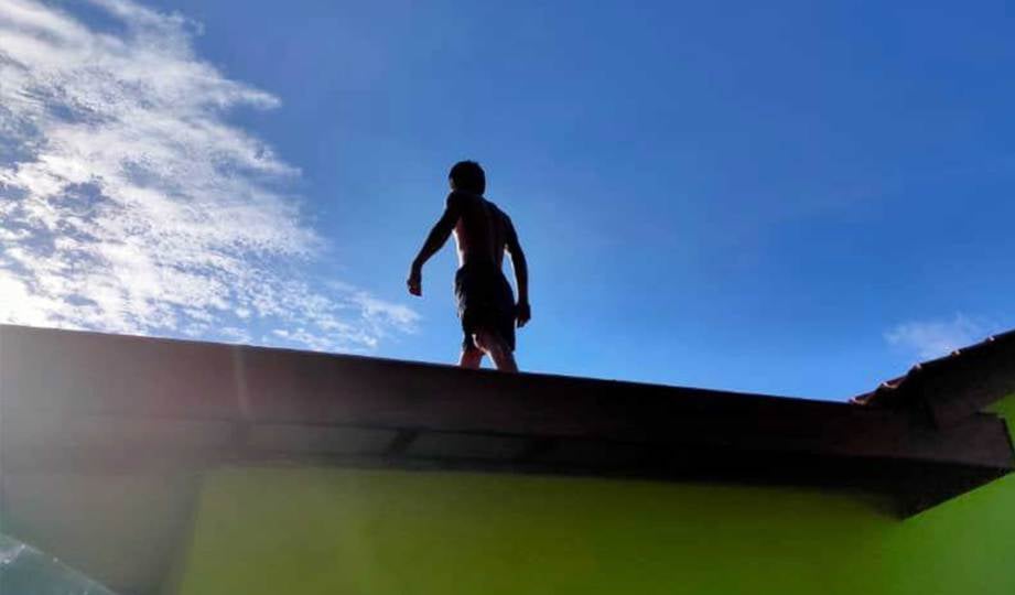 AKSI lelaki yang memanjat bumbung rumah selepas menyedari kehadiran AADK di Simpang Empat Sungai Daun, Yan. FOTO Ihsan AADK
