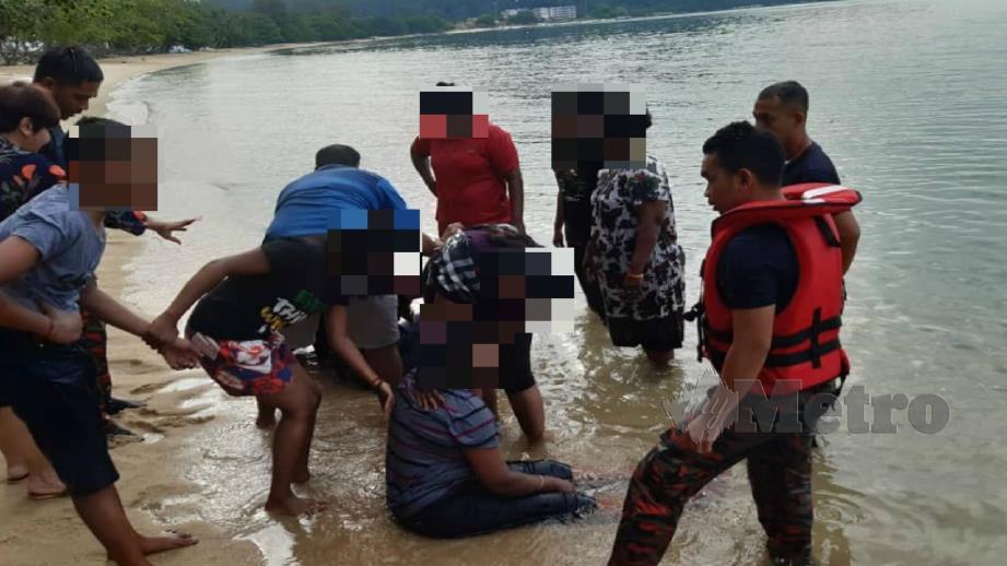 Anggota bomba melihat mangsa yang diselamatkan selepas hampir lemas di Pantai Pasir Bogak di Pangkor hari ini. Foto Ihsan JBPM