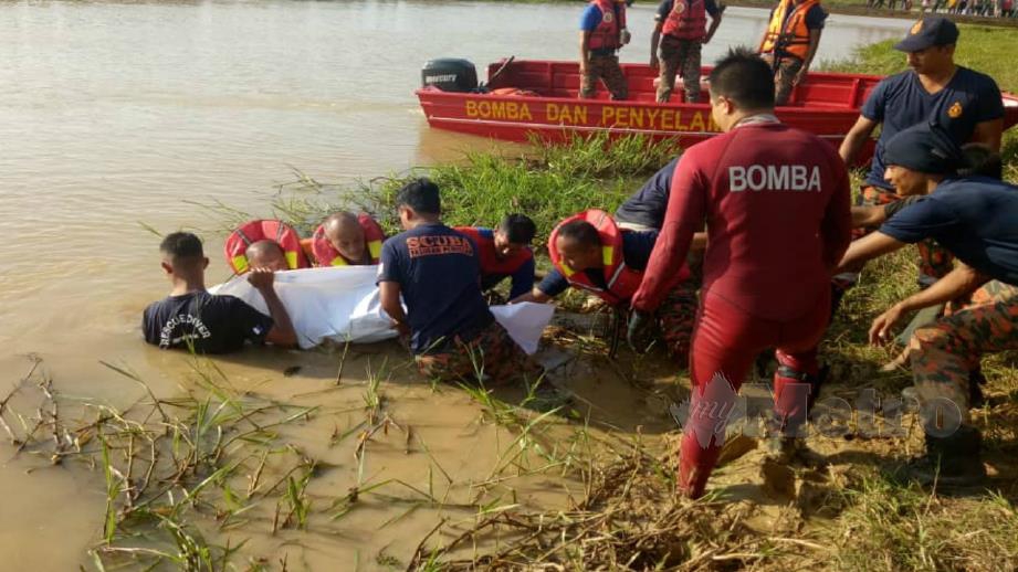 ANGGOTA bomba mengangkat mayat Muhamad Irfan selepas ditemui lemas di Sungai Santap, Pokok Sena. Foto Zuliaty Zulkiffli