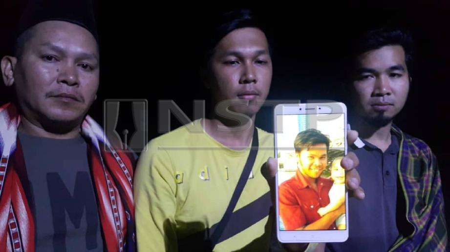 MUHAMMAD Faris (tengah) bersama ahli keluarga menunjukkan gambar Mohd Faiz yang lemas dalam kejadian di Bachok, malam tadi. 