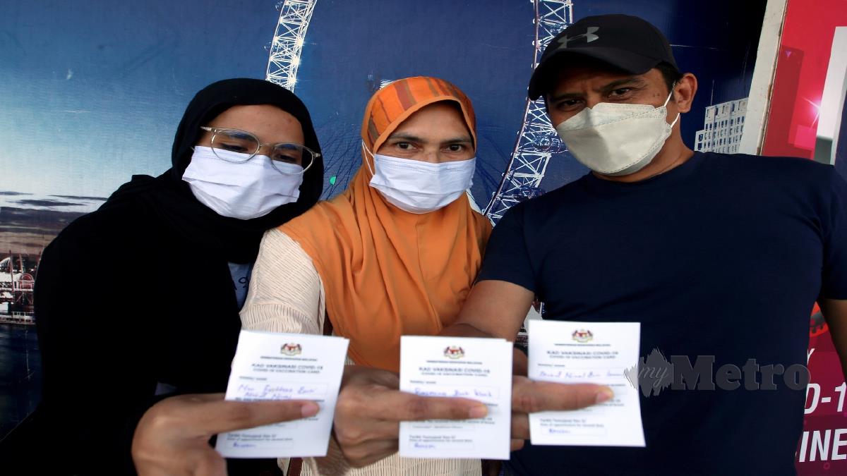 MOHD Nizal Ismail, 48, (kanan) bersama isteri Rusmiza Ishak, 48, dan anaknya, Nur Faatihah, 21, menunjukkan kad vaksinasi selepas mendapatkan suntikan dos penggalak vaksin Covid-19 di Pusat Pemberian Vaksin (PPV) Offsite Tapak Ekspo Seberang Jaya di sini. FOTO DANIAL SAAD
