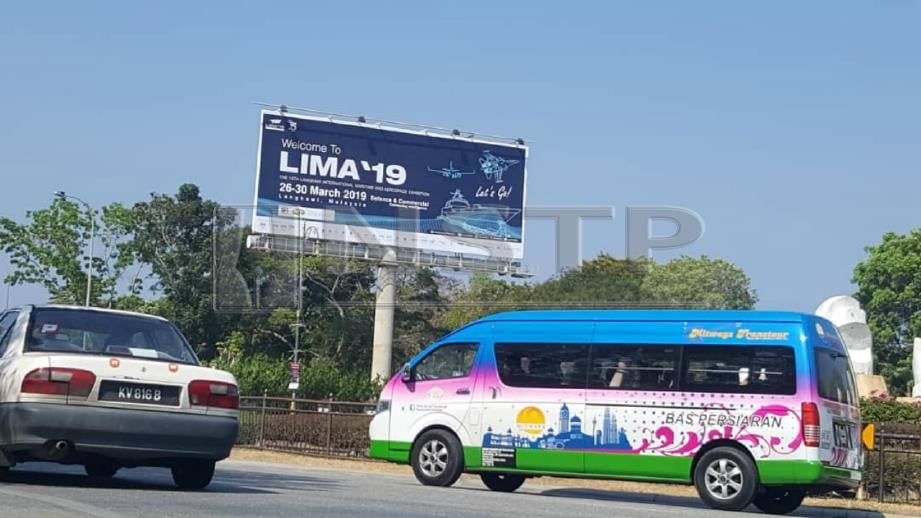  KENDERAAN melintasi papan tanda gergasi LIMA'19 yang di pasang di bulatan berhampiran Lapangan Terbang Antarabangsa Langkawi. FOTO Hamzah Osman
