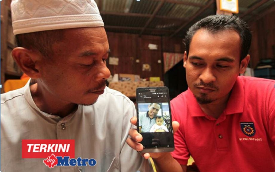 Mohd Sukri (kiri) bersama anak sulungnya, Mohd Ridhuan, 30, menunjukkan gambar Allahyarham Muhammad Lailatulman yang meninggal dunia di Bilik Tahanan Unit Sungai Wangi, Sitiawan, Ipoh, semalam, ketika ditemui di rumahnya di Kampung Bagus Rantau Panjang. FOTO SYAMSI SUHAIMI