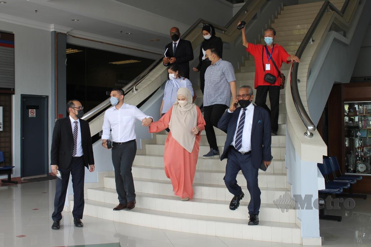 NEELOFA dipimpin Muhammad Haris ketika menuruni tangga kompleks mahkamah, hari ini. FOTO MOHD AMIN JALIL 
