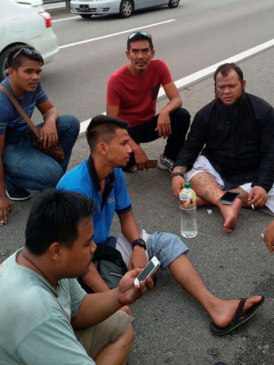 ABANG Long Fadhil (kanan) duduk di tepi lebuh raya selepas terbabit kemalangan.