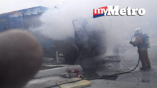 Anggota bomba memadamkan kebakaran lori sampah yang terbakar berhampiran stesen minyak di Mambau, pagi tadi. FOTO ihsan bomba