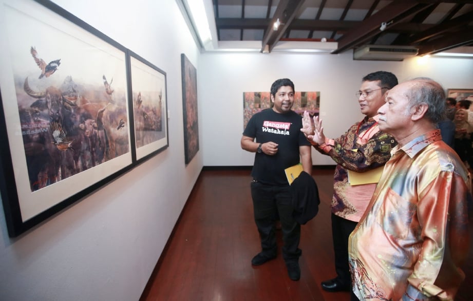 MOHAMMAD Farid (tengah) tertarik melihat lukisan ber konsep alam diiringi Raja Zahabuddin (kanan) selepas merasmikan Pameran Seni Ekspresi Malindo. FOTO Sairien Nafis