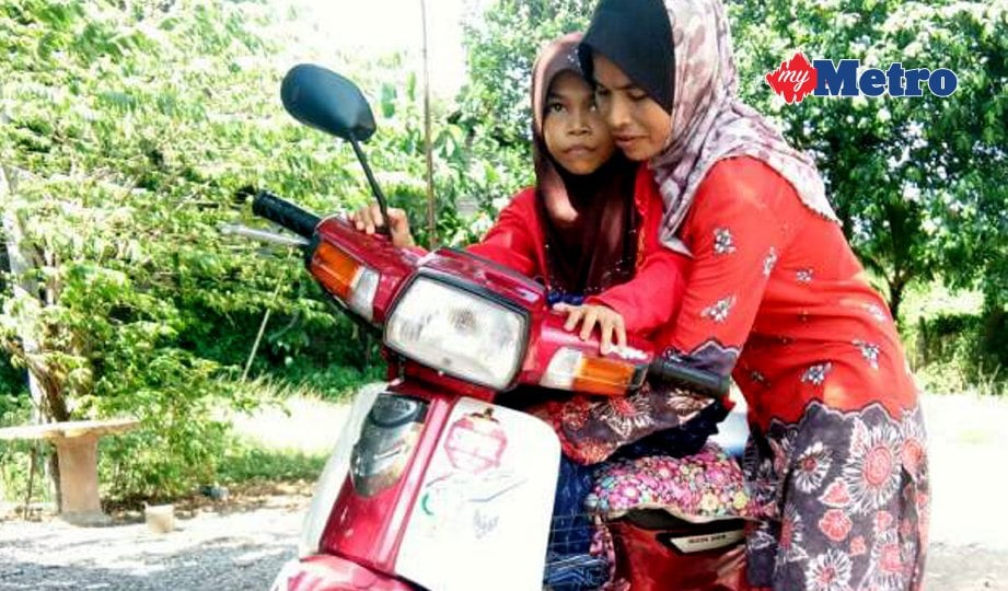 FATIMAH menggunakan motosikal untuk membawa anaknya Aziana yang lumpuh selepas  ditimpa batu konkrit. FOTO Nor Farhani Che Ad 