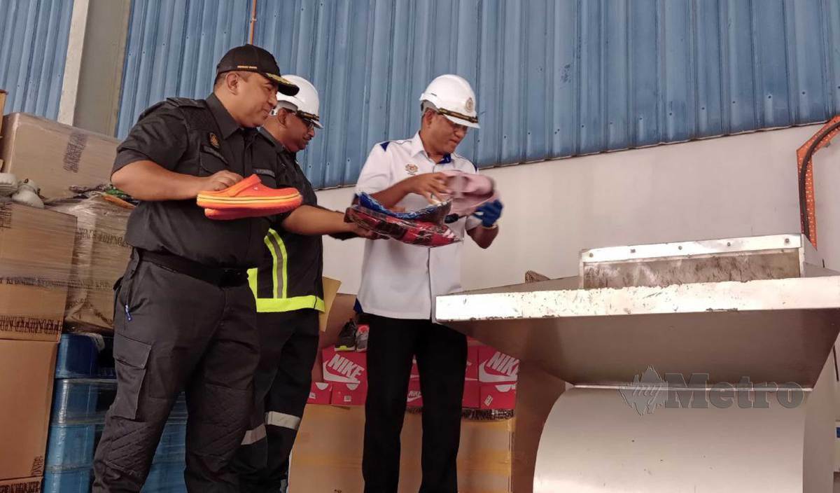 AZMAN memasukkan kasut tiruan ke dalam mesin khas pada Majlis Pelupusan Ekshibit Mega 2022 di Kompleks Penyimpanan Ekshibit Bahagian Penguat Kuasa KPDNHEP, Nilai. FOTO Mohd Amin Jalil
