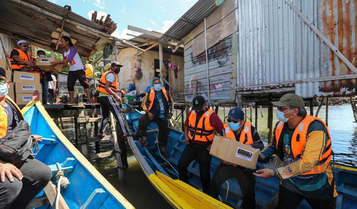PETUGAS Muslim Care Malaysia mengangkat barang sumbangan daripada bot untuk diagihkan kepada penduduk Kampung Kuala Balong pada Misi Santuni Asnaf Sabah anjuran Muslim Care Malaysia. FOTO Aswadi Alias