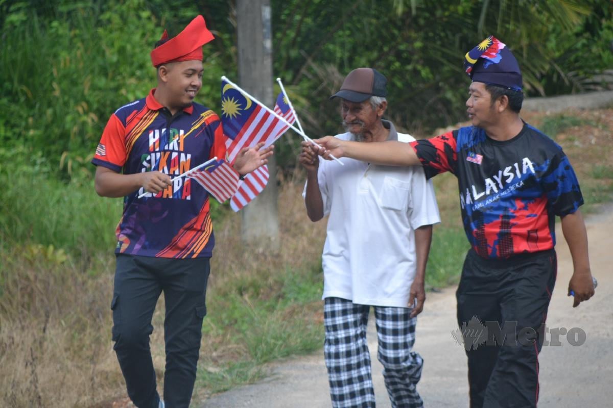 Md Din (tengah) bersemangat berarak bersama-sama Rozaidi (kanan) dan anak kariah Kampung Solok Air Budi, Durian Daun, Masjid Tanah meraikan Hari Kebangsaan. FOTO HASSAN OMAR
