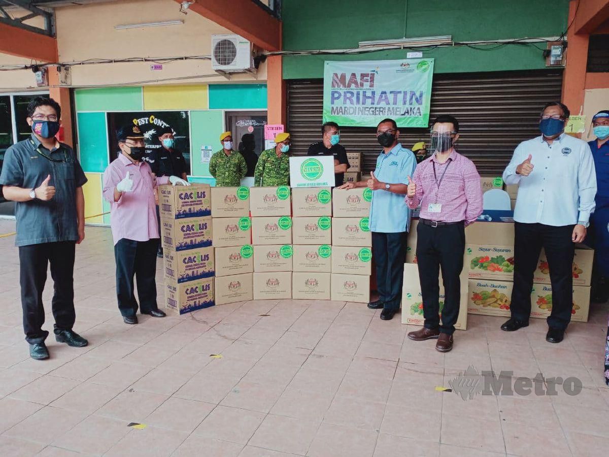 AHMAD (bertopi) menyerahkan sumbangan makanan dan buah-buahan kepada petugas di PPV Dewan Seri Umbai. FOTO Amir Mamat