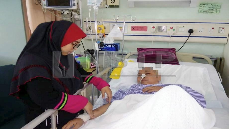 SITI Aisyah Mah menguruskan ibunya, Siti Asmara  yang menerima rawatan di Hospital Enche Besar Hajjah Khalsom (HEBHK), Kluang, hari ini. Foto ADNAN IBRAHIM