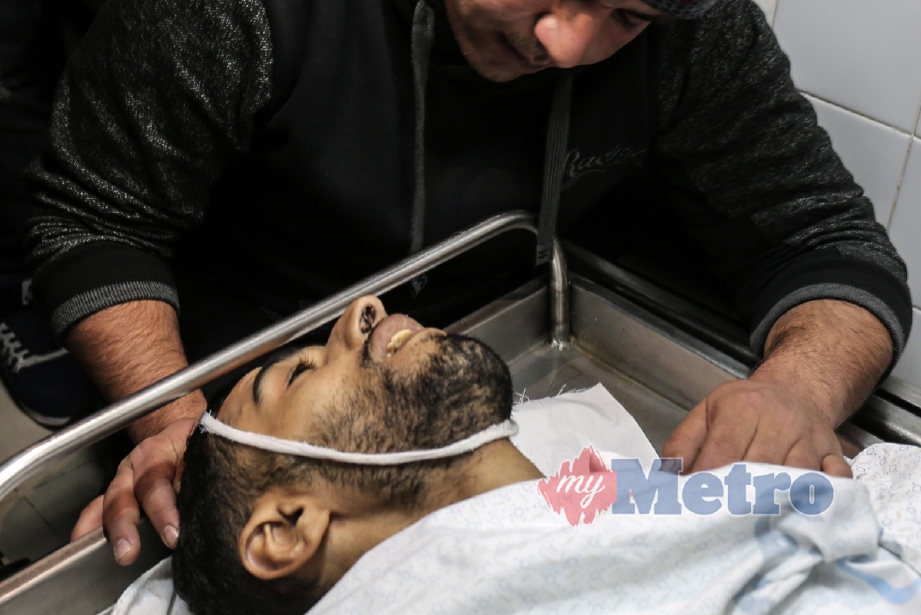 SAUDARA Mahmoud al-Masri, 30, melihat jenazahnya selepas dia mati ditembak tentera Israel ketika menyertai bantahan di Khan Yunis, Gaza. - Foto AFP