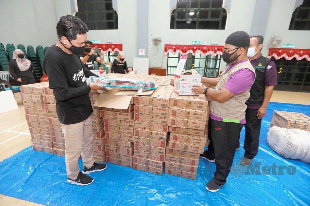 ASMADI (kanan) dan Nur Mukshar melihat sebahagian barangan bantuan pasca banjir PPZ-MAIWP bernilai RM70,000 untuk mangsa banjir daerah Pekan. FOTO Mohd Rafi Mamat