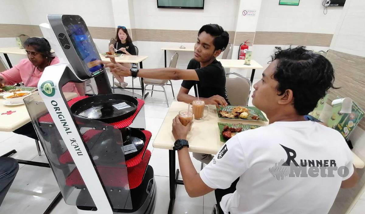 PELANGGAN di Restoran Kayu Nasi Kandar Original Penang, Bukit Jambul teruja apabila pesanan minuman mereka dihantar robot pelayan. FOTO Zuhainy Zulkiffli
