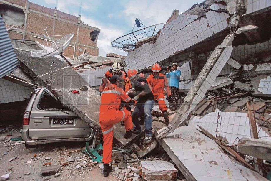 ANGKOTA keselamatan sedang mengeluarkan mangsa daripada runtuhan. FOTO/AFP 
