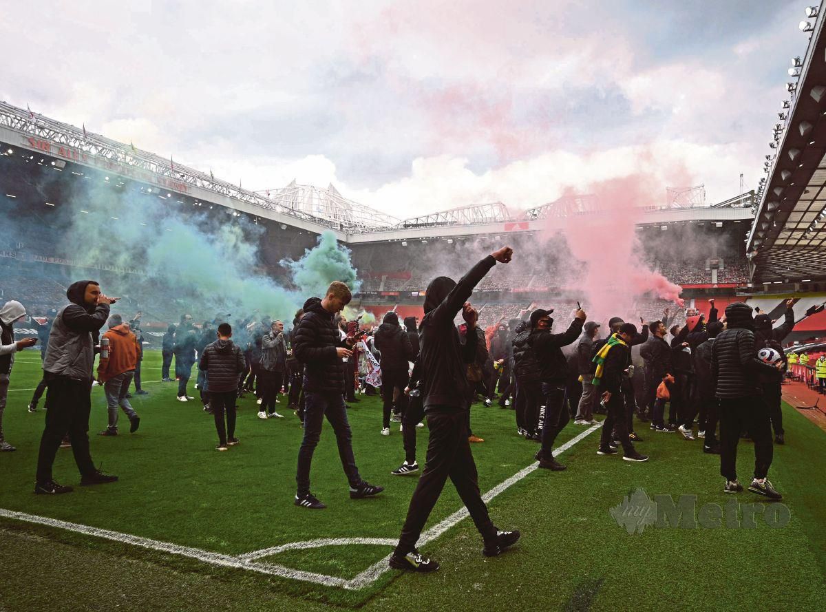 PENYOKONG Man United menceroboh masuk ke padang Old Trafford yang menyebabkan perlawanan dengan Liverpool terpaksa ditangguhkan. FOTO AFP