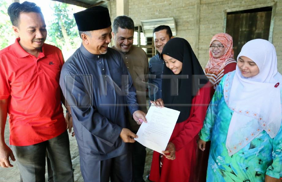 AMIRUDDIN (dua dari kiri) melihat surat tawaran kemasukan ke MRSM Nurul Syafika (tiga dari kanan). FOTO Amran Hamid