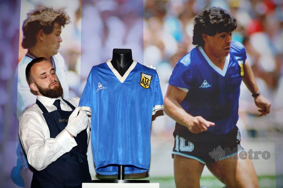 KAKITANGAN Sotheby memegang jersi Maradona. FOTO AFP