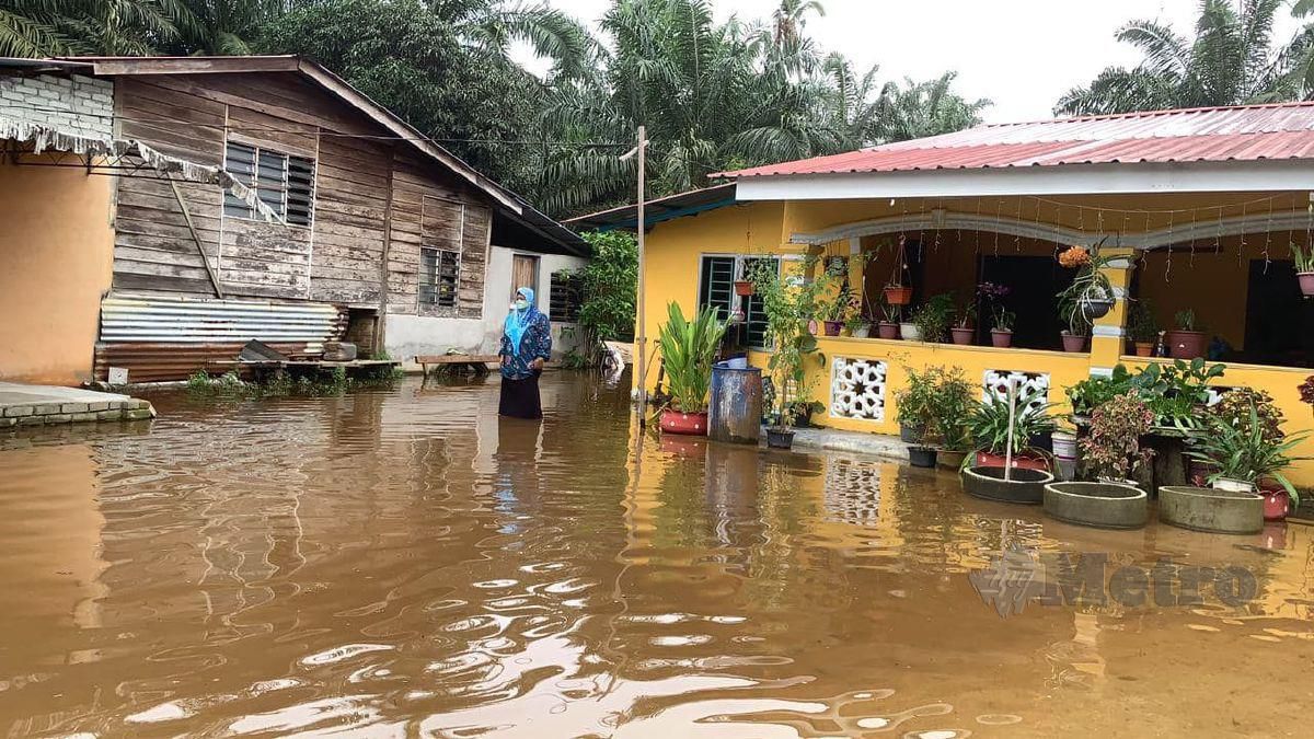 Mariani di halaman rumahnya yang dinaiki air akibat hujan lebat berterusan di Kampung Padang Serai, Pantai Remis di Manjung. FOTO NOOR HIDAYAH TANZIZI