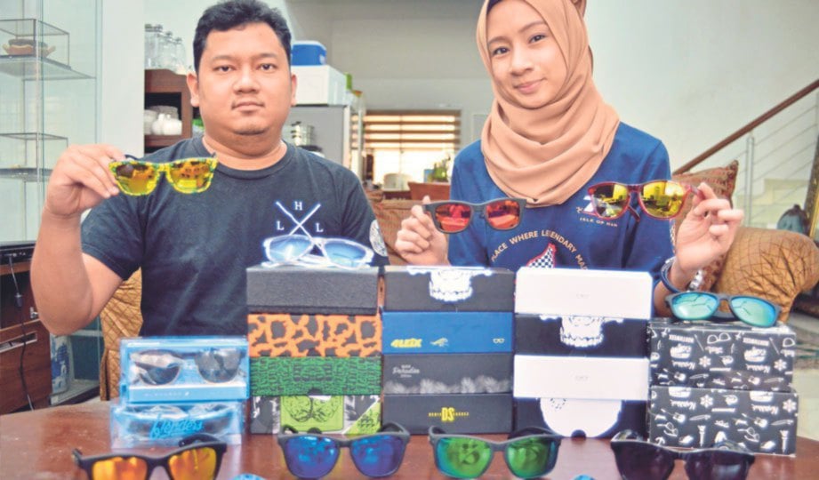 MUHAMMAD Fatimi  (kiri) dan Nur Farahiyah menunjukkan  cermin mata hitam pelbagai jenis yang dijual.