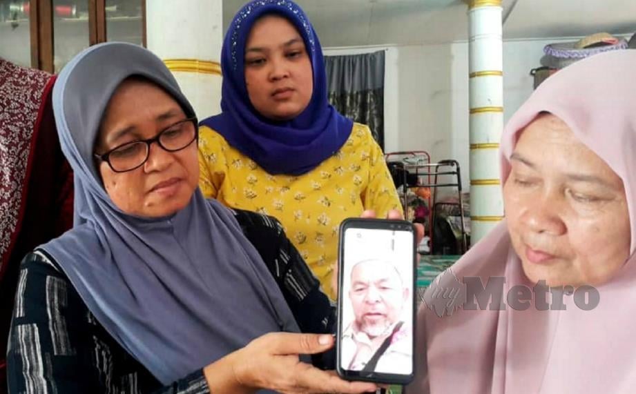 TUAN Kembang (kiri) menunjukkan gambar Allahyarham Ismail yang meminta supaya mendoakan dia sihat dan dapat menunaikan haji dengan baik ketika ditemui di Kampung Telaga Papan, Pasir Puteh, hari ini. FOTO Nor Amalina Alias.