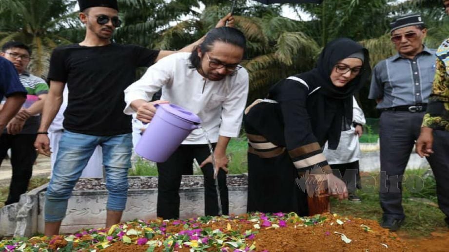MAWI bersama isteri, Nora Asyikin Rahmat menyiram air mawar di kubur ibunya. FOTO Zain Ahmed 