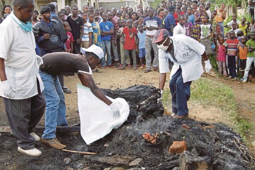 ANGGOTA polis DRC mengutip sisa mayat seorang lelaki yang dibakar  oleh sekumpulan penduduk di Beni, di utara negara itu, semalam.