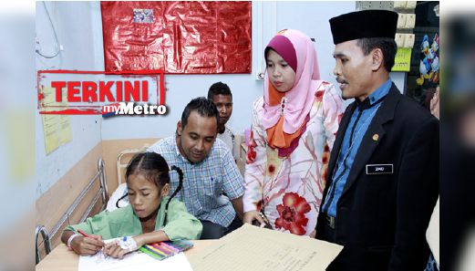 Norieen menulis dan melukis sambil diperhatikan Ketua Pemuda UMNO Kelantan, Mohammad Azam Ismail (duduk) dan Pegawai Perhubungan Awam HRPZ II, Zaid Ahmad (kanan). FOTO Nik Abdullah Nik Omar