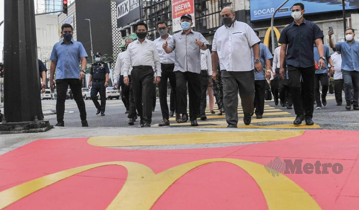 SHAHIDAN (tengah)  bersama Azmir (kiri) melintasi lintasan pejalan kaki "Fries" McDonalds selepas Majlis Pelancaran Lintasan Pejalan Kaki "Fries" McDonalds di Jalan Bukit Bintang, Kuala Lumpur. FOTO Aizuddin Saad