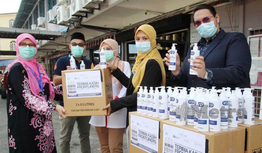 AZIZAH (kiri) menerima sumbang 500 botol cecair pembasmi kuman dari Medikel Pharmacy di Bahagian Perkhidmatan Farmasi Jabatan Kesihatan Negeri Kelantan. FOTO Nik Abdullah Nik Omar